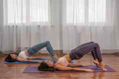 年轻的女士健身教练紫罗兰色的运动服装紧身裤前伸展运动健身房普拉提瑜伽席大窗口阳光明媚的一天女健身瑜伽例程概念