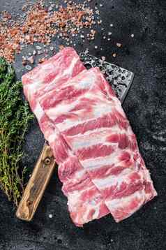 未煮过的生猪肉备用肋骨屠夫肉切肉刀黑色的背景前视图
