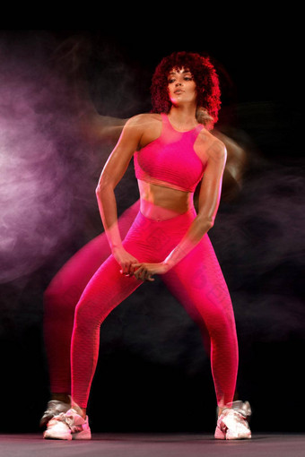 快乐年轻的健身女人跳舞黑色的背景烟混合照明摄影