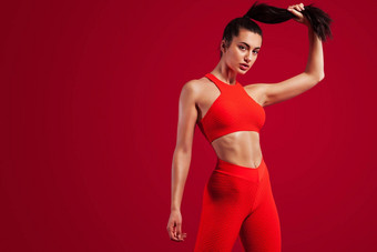 强大的运动女人舞者摆姿势红色的背景穿运动服装健身体育运动动机复制空间