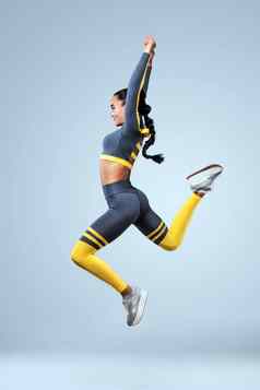 有吸引力的兴奋健身女孩舞者运动服装跳快乐孤立的灰色的背景