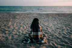 女人坐着沙子海滩前面海