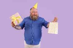 兴奋脂肪男人。聚会，派对他持有礼物纸袋紫色的背景