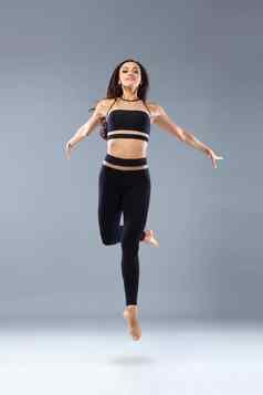 有吸引力的兴奋健身女孩芭蕾舞女演员舞者运动服装跳快乐孤立的灰色的背景