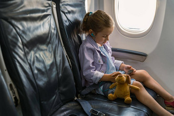 女孩坐着椅子玩具持有电话旅行飞机