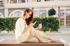 女人坐着板凳上杯咖啡移动电话