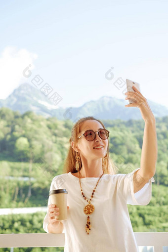 快乐女人采取自拍照片背景夏天山
