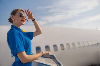 肖像优雅的空气空姐蓝色的统一的太阳镜持有手头站空中楼梯白天