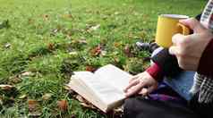 女孩坐在毯子秋天森林读取书饮料热喝黄色的杯城市公园温暖的一天绿色草地概念阅读放松安慰