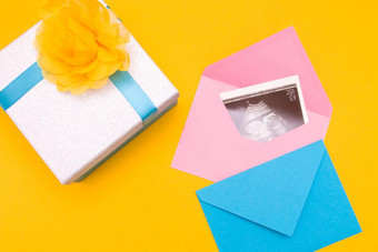 超声波图片银盒子蓝色的丝带黄色的花黄色的背景的地方复制前视图女人怀孕了男孩女孩惊喜照片礼物怀孕概念