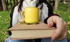 女孩穿着外套围巾秋天森林持有书杯热喝手特写镜头城市公园温暖的一天概念阅读放松安慰