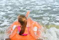 孩子女孩浮动橙色池环背景海水波