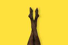 长纤细的腿年轻的女人黑色的老虎打印连裤袜黄色的背景