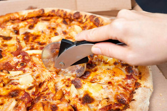 关闭手切割<strong>披萨披萨</strong>刀美味的paperoni<strong>披萨</strong>开放盒子孤立的黑色的背景前视图paperoni<strong>披萨</strong>概念意大利食物街食物快食物快速咬