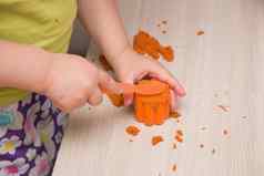 孩子们的手按橙色沙子模具玩具松饼蛋糕米色木表格