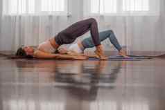 年轻的女士健身教练紫罗兰色的运动服装紧身裤前伸展运动健身房普拉提瑜伽席大窗口阳光明媚的一天女健身瑜伽例程概念