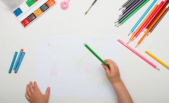 孩子手持有绿色铅笔吸引了写白色一块纸白色背景前视图的地方复制回来学校刻字油漆铅笔刷粉红色的笔甜甜圈