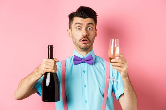 假期庆祝活动概念困惑男人。盯着吓了一跳相机倒玻璃香槟站困惑粉红色的背景