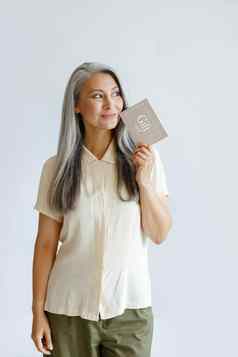 深思熟虑的古老的头发的亚洲夫人客户持有礼物卡站光灰色背景
