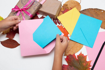 孩子们的手把卡信封明亮的颜色礼物美丽的丝带假期感恩节生日秋天叶子白色表格复制空间前视图粉红色的黄色的蓝色的