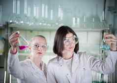 化学实验室年轻的漂亮的女人持有烧瓶液体瓶