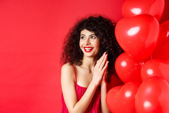 兴奋美丽的女人卷曲的头发站<strong>心气球</strong>摩擦手掌预计好交易享受红色的背景
