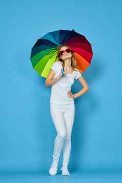 时尚女人伞彩虹颜色摆姿势蓝色的背景