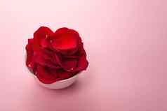 美丽的红色的玫瑰花瓣白色碗温柔的粉红色的背景玫瑰花瓣香水化妆品洗澡