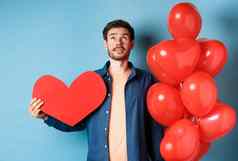 情人节一天爱概念男人。梦幻脸持有浪漫的礼物气球红色的心断路站蓝色的背景