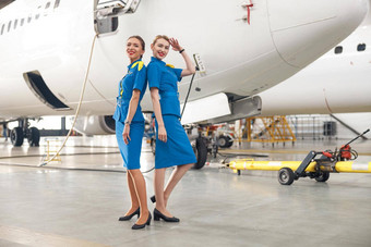 完整的<strong>长度</strong>拍摄漂亮的空气空姐明亮的蓝色的统一的微笑相机摆姿势前面乘客飞机机库机场