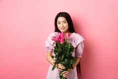 浪漫的温柔的亚洲女孩持有花束玫瑰微笑可爱的相机情人节日期情人穿衣服粉红色的背景