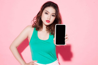 肖像快乐的女人显示空白智能<strong>手机屏</strong>幕粉红色的背景焦点智能手机