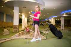 年轻的金发女郎女人站高尔夫球俱乐部坚持袋持有高尔夫球坚持肩膀摆姿势