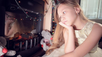 伤心失望女孩坐在人工壁炉伤心软玩具概念被宠坏的圣诞节假期