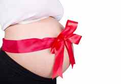 关闭怀孕了女人红色的丝带礼物肚子孤立的白色
