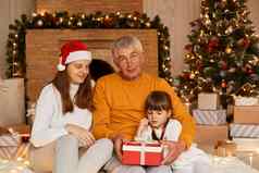 室内拍摄快乐家庭给圣诞节现在可爱的黑暗头发的女孩红色的包装礼物盒子摆姿势装饰生活房间圣诞节树壁炉