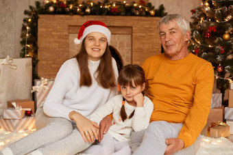 肖像快乐家庭成熟的男人。穿橙色毛衣女儿（外）孙女坐着圣诞节树首页相机积极的面部表达式