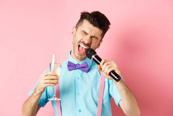 聚会，派对节日事件概念喝醉了有趣的的家伙唱歌麦克风喝香槟玻璃有趣的卡拉ok酒吧站粉红色的背景