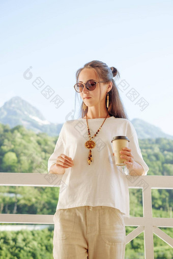 美丽的女人休息杯咖啡阳台前面山