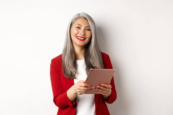 业务成功的高级女商人工作数字平板电脑微笑站红色的夹克白色背景