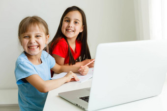 很酷的在线学校孩子们研究在线首页移动PC快乐的年轻的女孩移动PC电脑研究在线电子学习系统距离远程学习