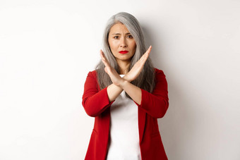 亚洲高级女人红色的夹克使交叉手势恳求停止不同意不赞成站白色背景