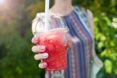 女人手持有红色的冰水塑料杯冰饮料冷健康的夏天喝鸡尾酒