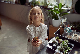 年轻的快乐高加索人孩子女孩持有植物手植物商店
