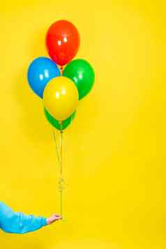 女手持有群色彩斑斓的气球聚会，派对现在概念绿色红色的黄色的蓝色的气球手孤立的黄色的使用