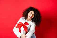 庆祝活动假期概念快乐女人持有生日礼物微笑相机站休闲衣服红色的背景