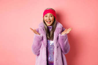 时尚购物概念快乐的亚洲上了年纪的女人紫色的时尚的外套惊讶听到好新闻欢乐站粉红色的背景