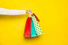 购物出售概念女手持有购物纸袋孤立的黄色的背景