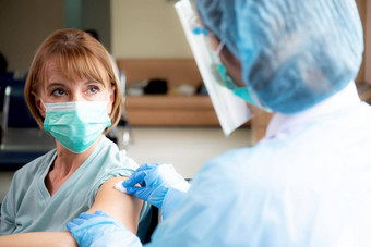 医生女人持有注射器注射疫苗病人上了年纪的脸面具预防冠状病毒医院疫苗接种流感大流行高级感染免疫接种医疗概念