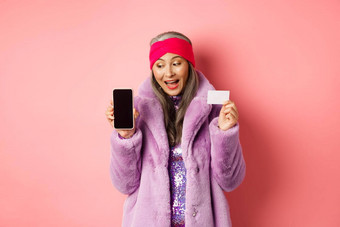 特殊的<strong>促销</strong>活动兴奋亚洲高级女人显示空白智能手机<strong>屏</strong>幕塑料信贷卡检查在线提供粉红色的背景